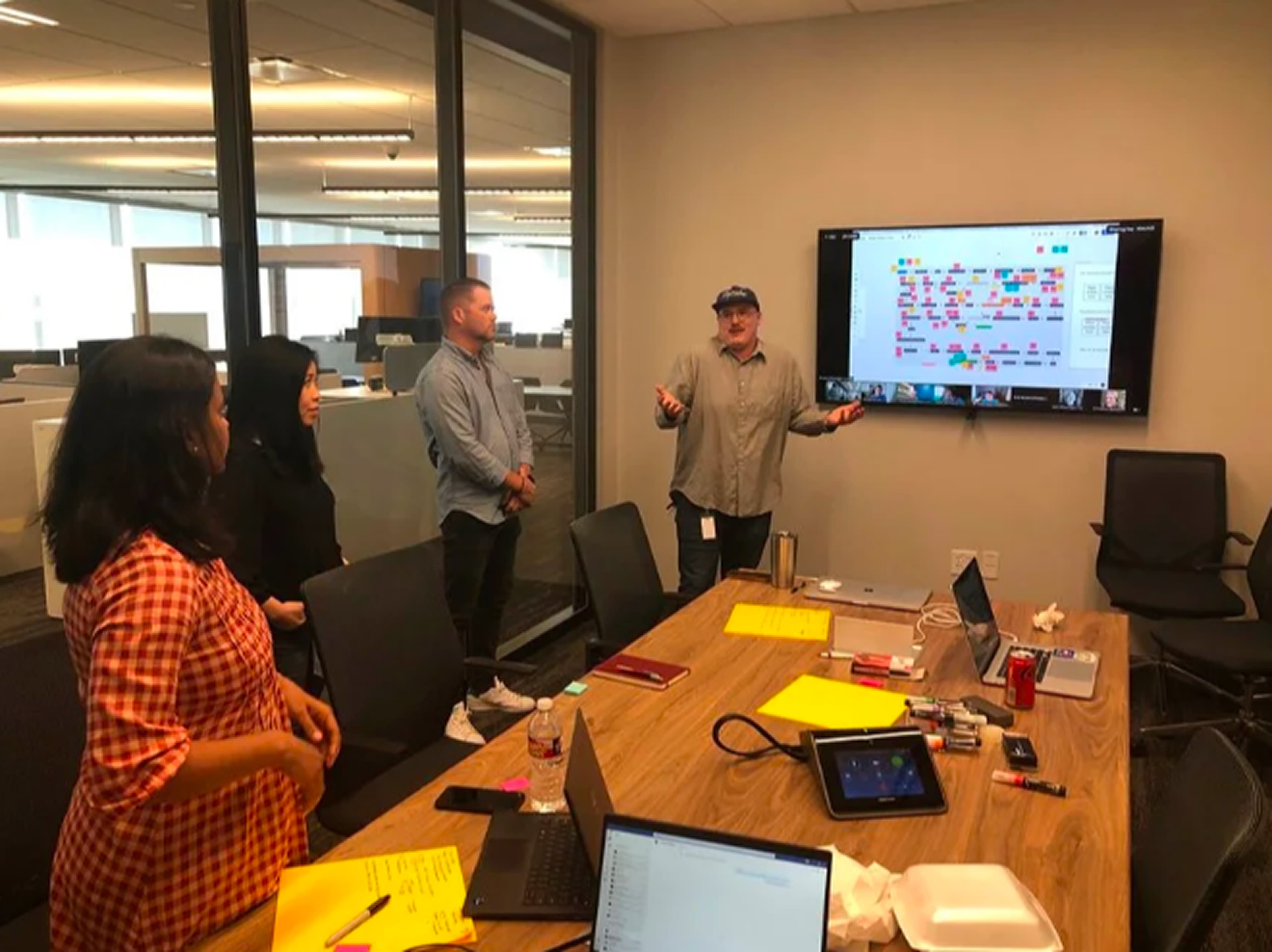 Team members standing around a conference table with a screen showing the e-signature flow, discussing the design direction during a cross-functional workshop